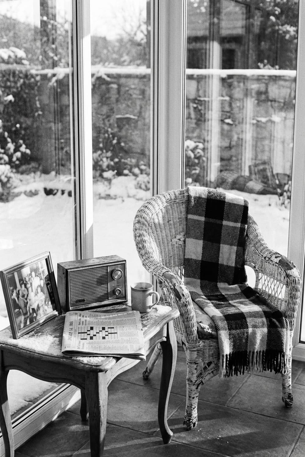 Winter Light, Inside Voices - sunroom, black and white, wicker chair, wooden table, radio - Room Inspiration